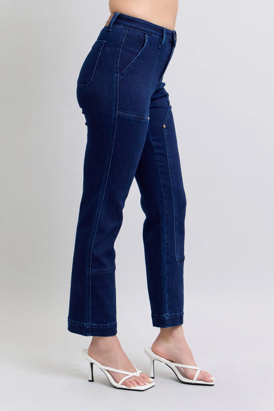 Dark blue jeans worn by a person on a light gray background