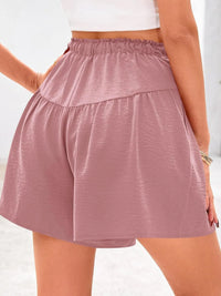 Person wearing a pair of pink shorts on a white background