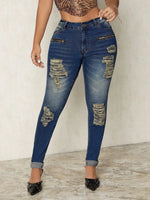 Person wearing distressed blue jeans on a plain background
