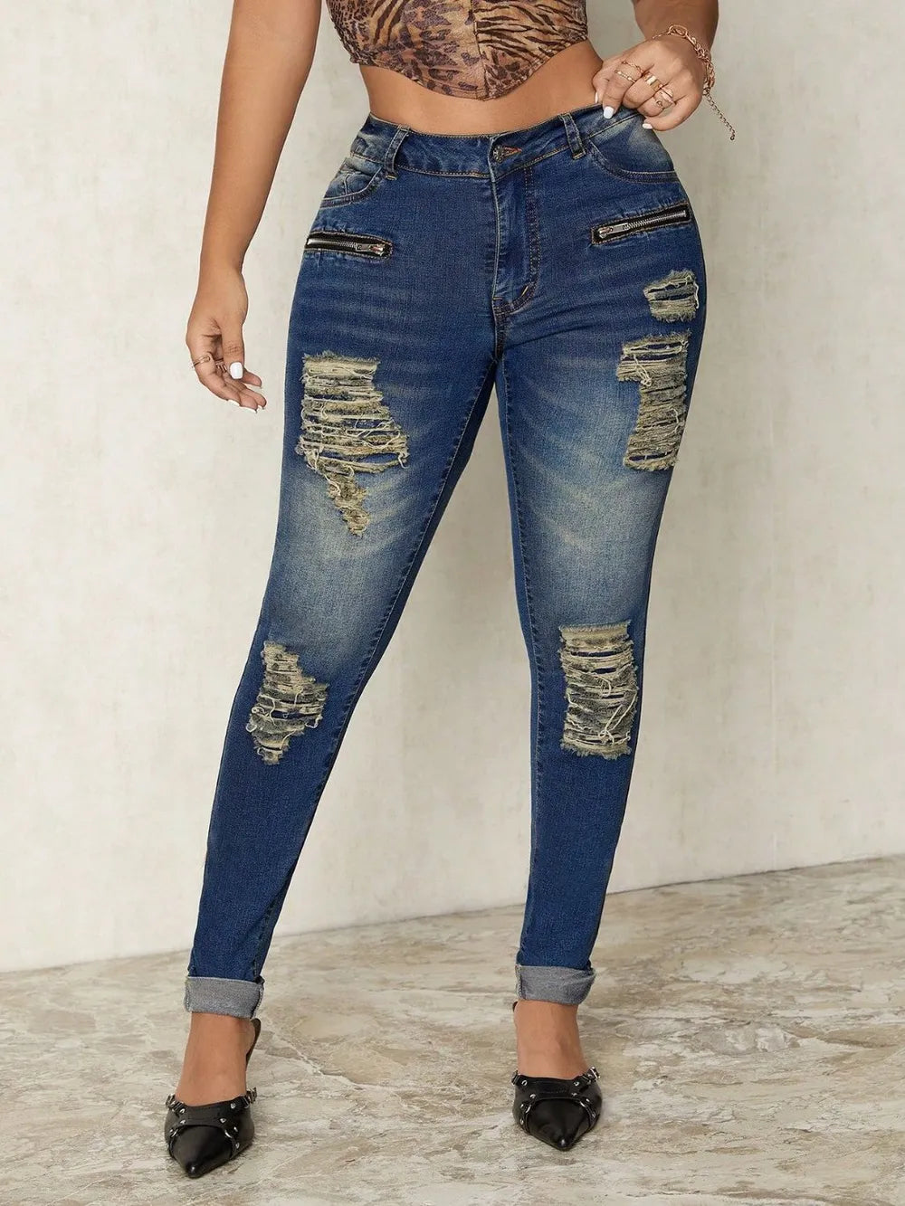 Person wearing distressed blue jeans on a plain background