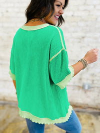 Woman wearing a green sweater with white trim against a blurred background