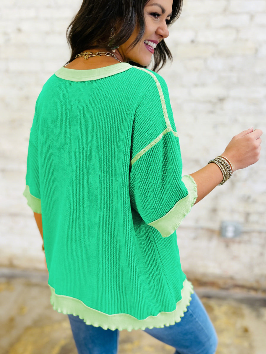 Woman wearing a green sweater with white trim against a blurred background