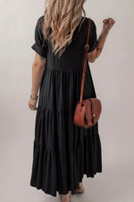 Person wearing a black dress holding a brown leather bag against a plain background