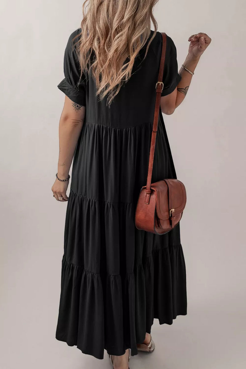 Person wearing a black dress holding a brown leather bag against a plain background