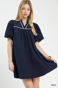 Woman wearing a navy dress with white trim on a white background