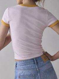 Person wearing a light purple t-shirt with yellow trim and blue jeans on a plain background