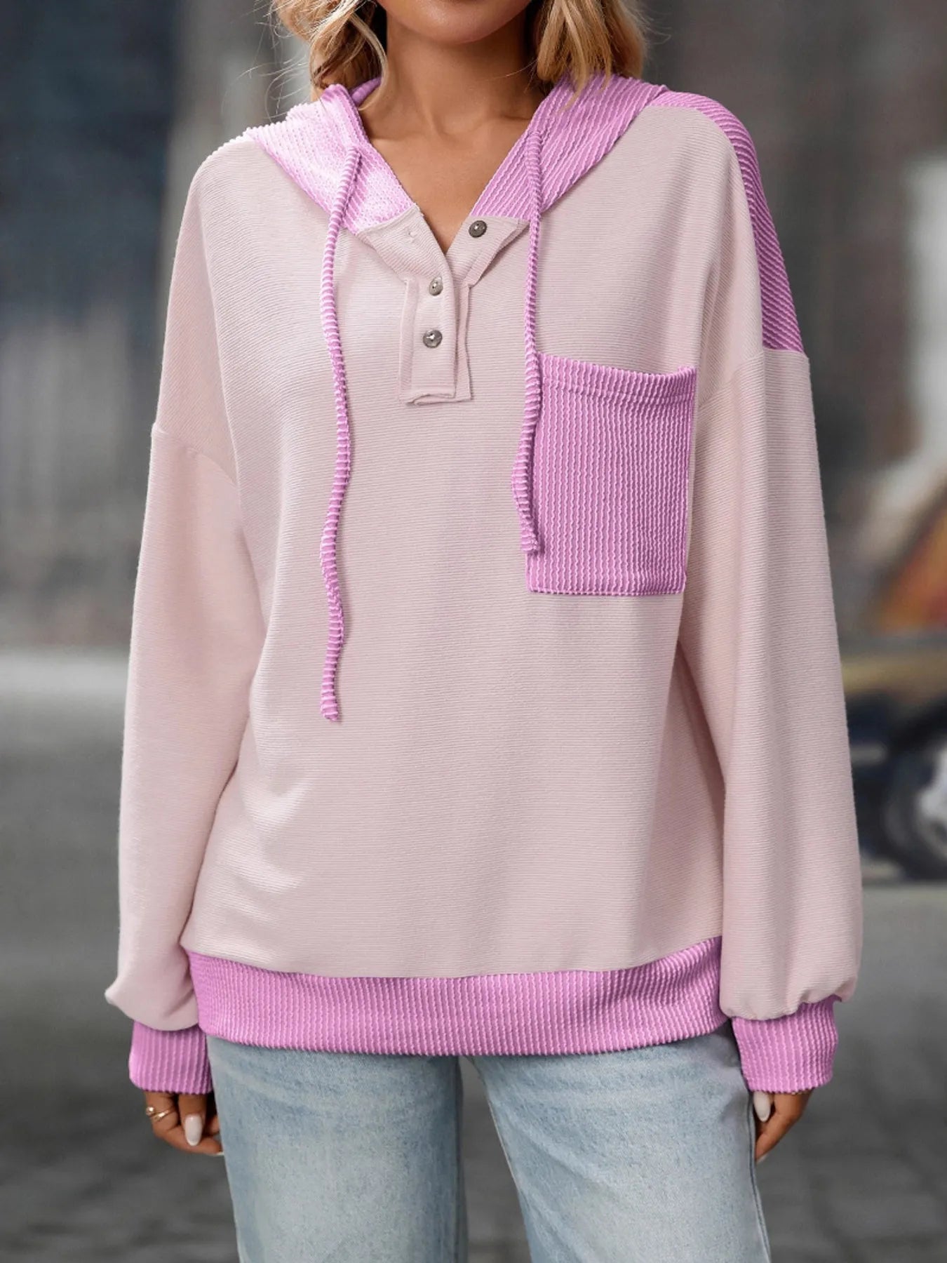 Light pink and purple hoodie worn by a person with a blurred background