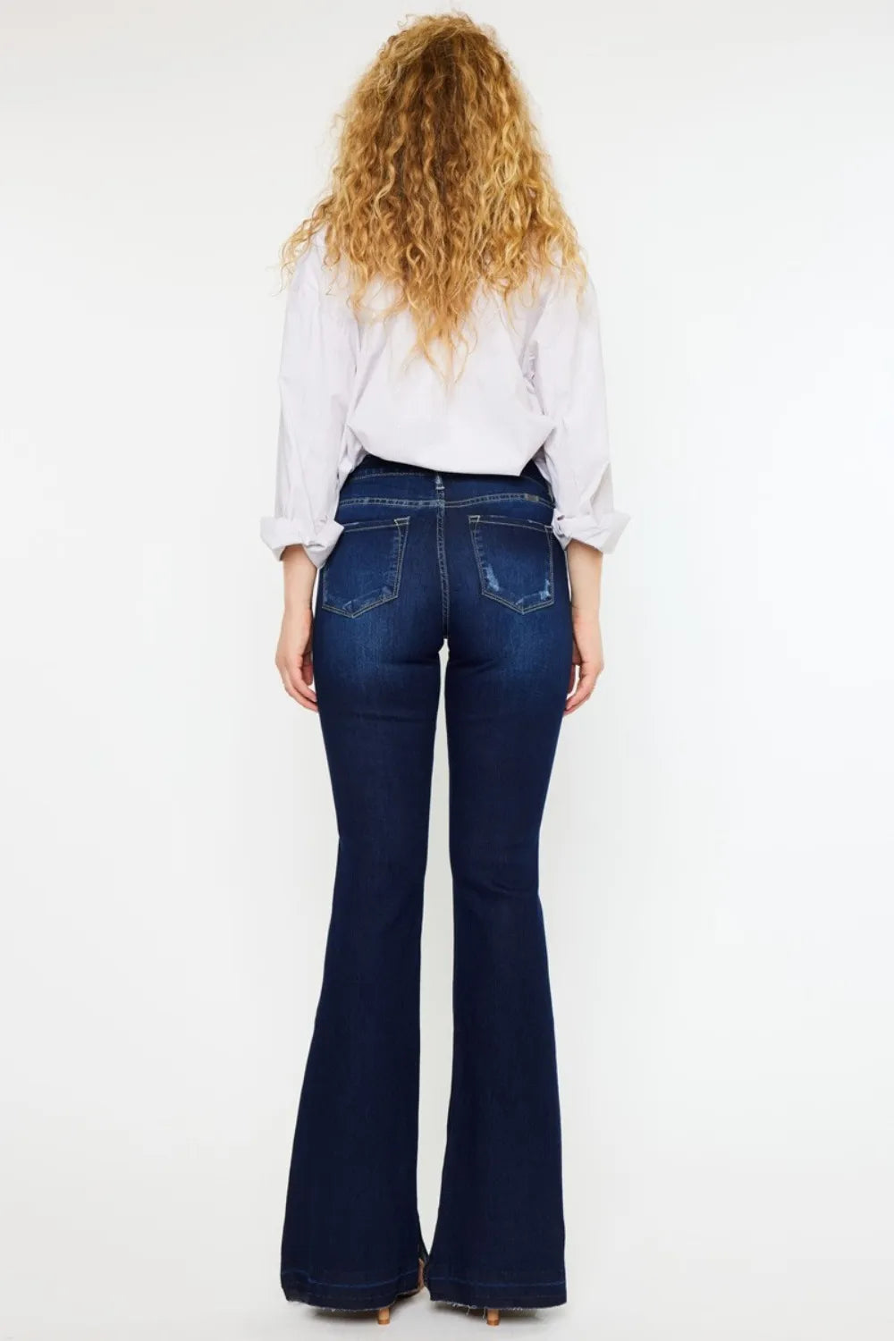 Person wearing blue flared jeans and a white shirt on a white background