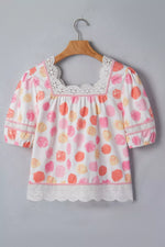 Floral blouse with lace details on a wooden hanger against a gray background