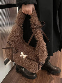Brown fluffy bag held by a person wearing black shoes on a wooden floor.