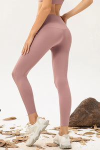 Person wearing pink leggings and white sneakers on a neutral background