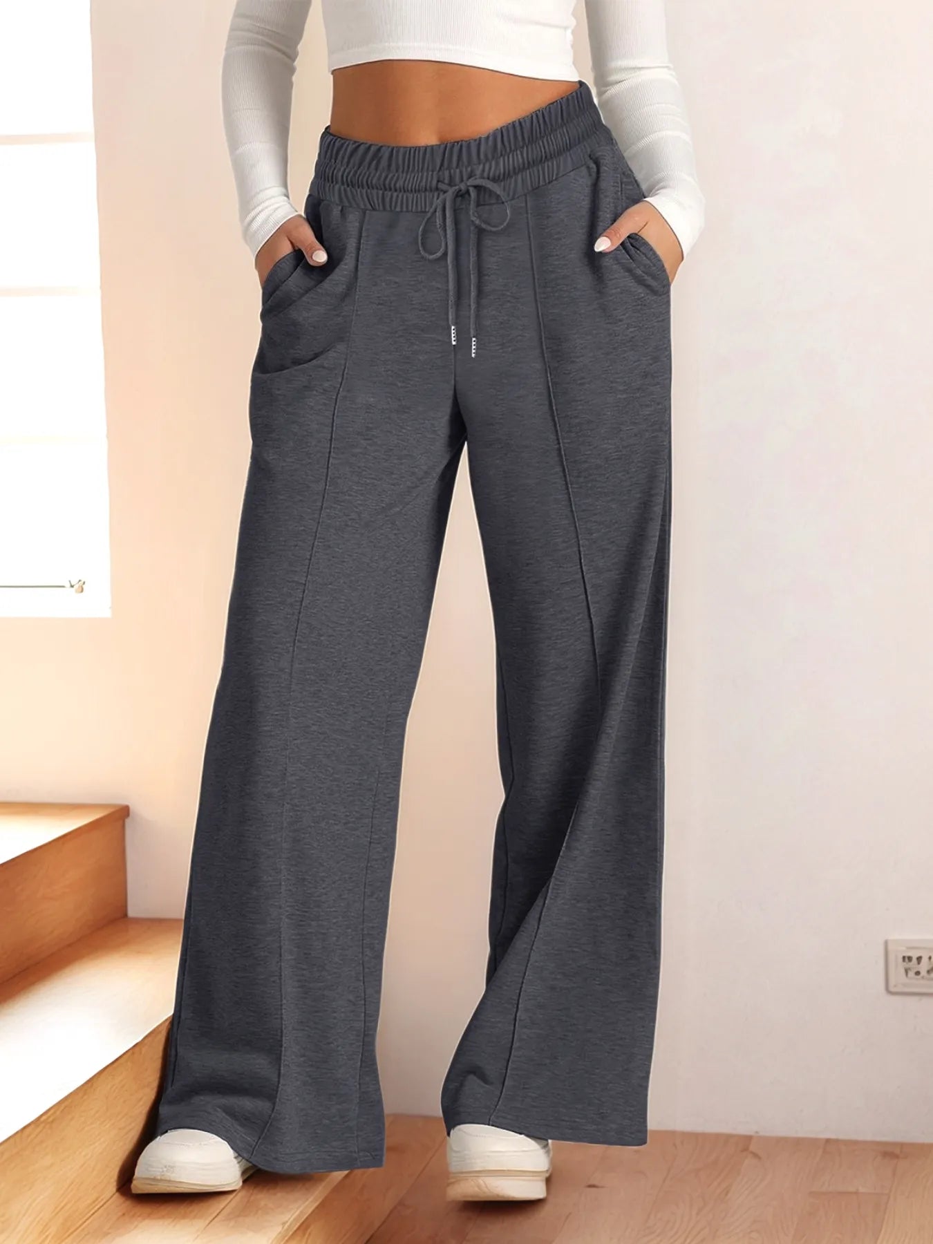 Person wearing gray sweatpants with a white top in a minimal indoor setting