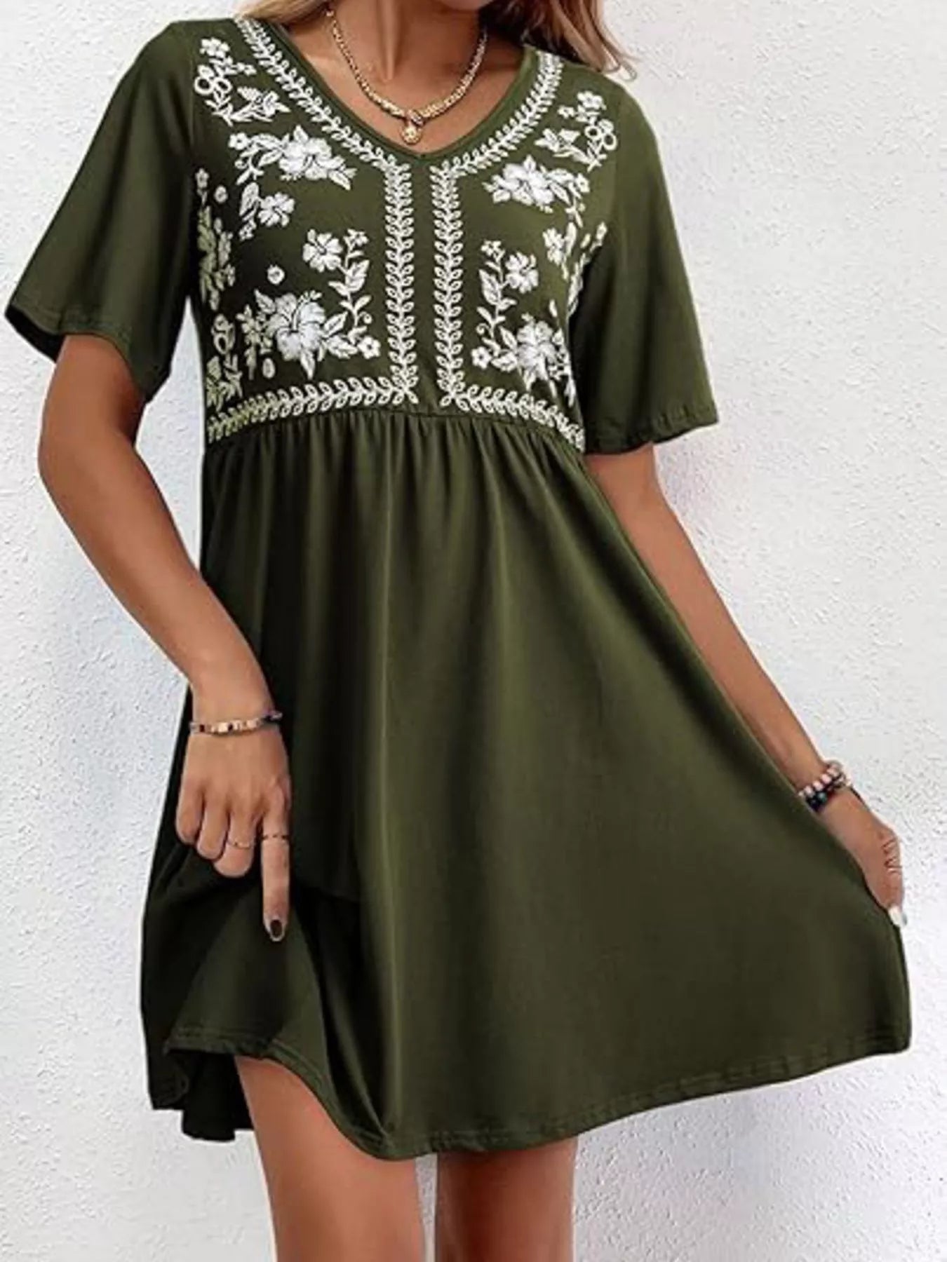Green dress with white floral embroidery on a white background