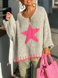 Person wearing a gray sweater with a pink star design, holding a pink bag.