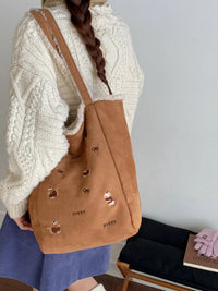 Person holding a brown tote bag with dog illustrations against a plain background