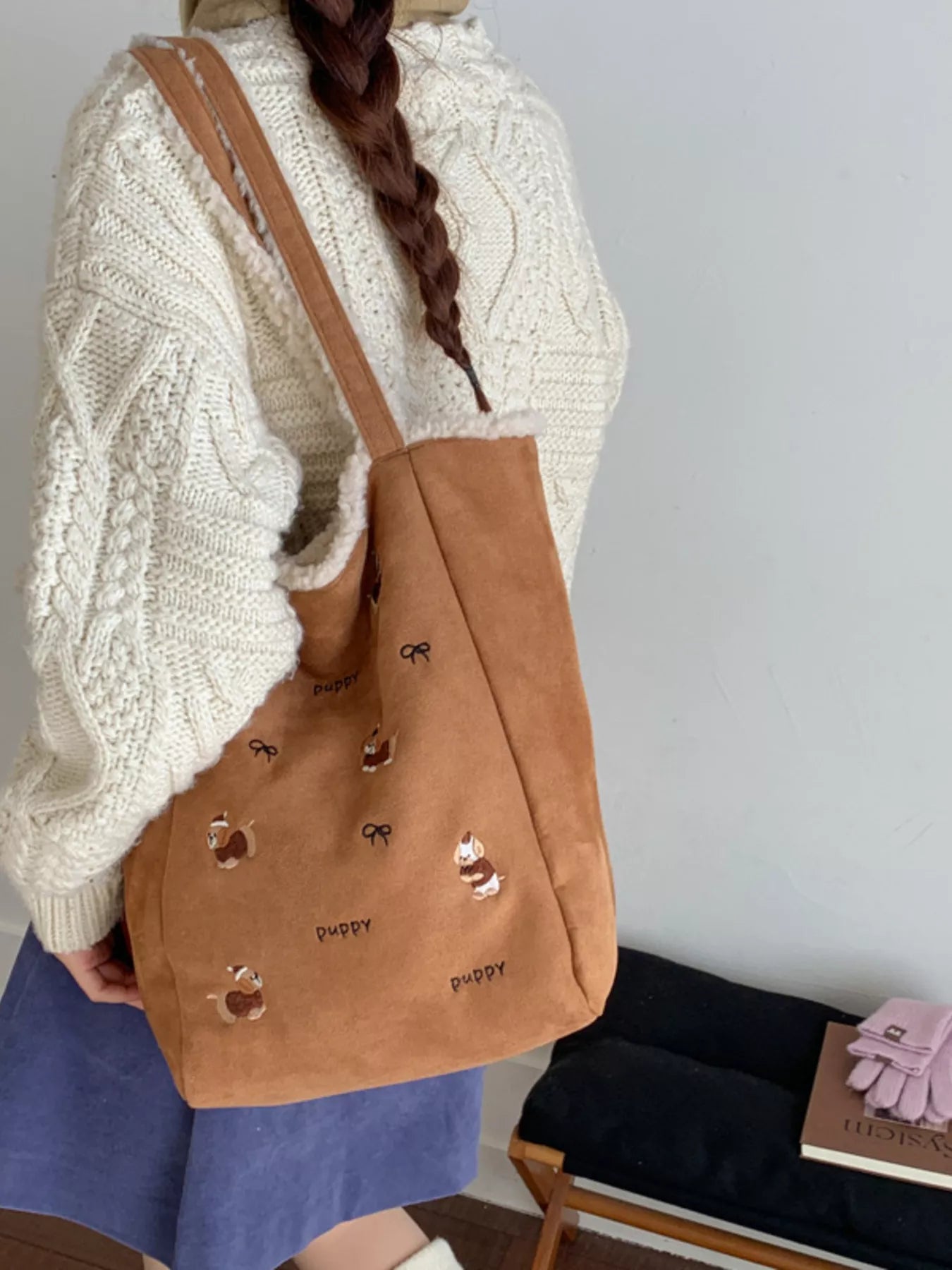 Person holding a brown tote bag with dog illustrations against a plain background