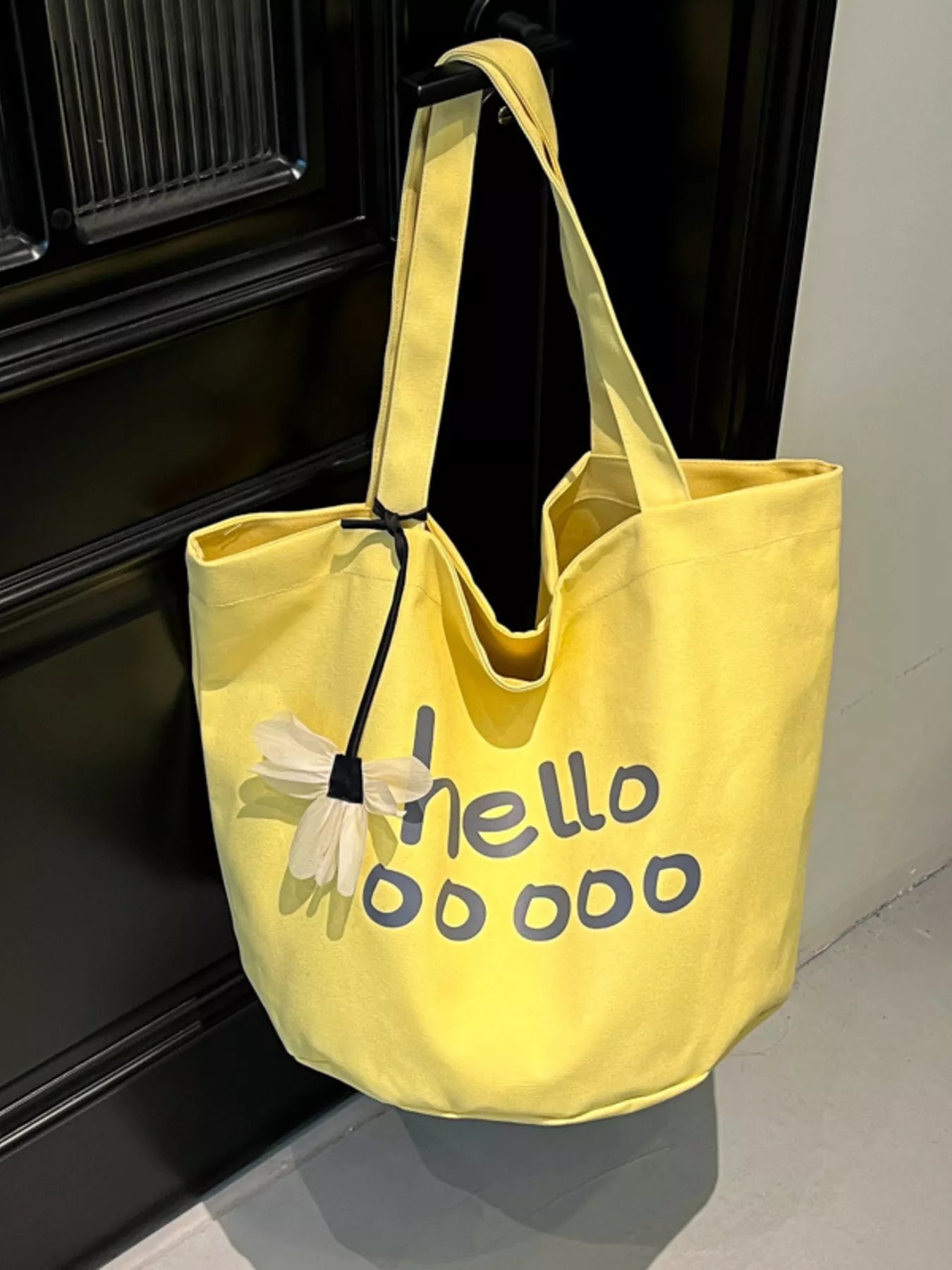 Yellow tote bag with floral design and text on a reflective surface