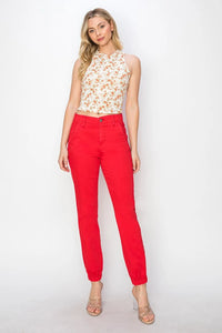 Woman wearing a floral top and red pants on a white background