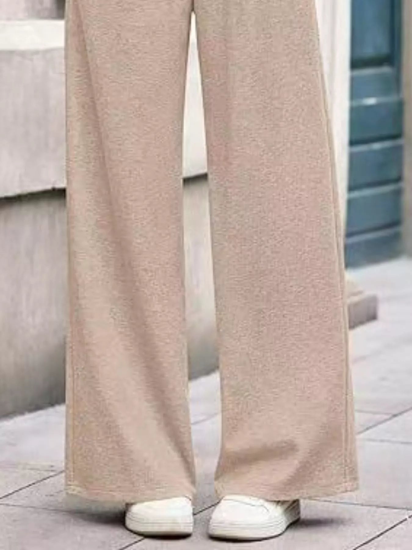 Beige wide-leg pants worn by a person on a tiled floor.