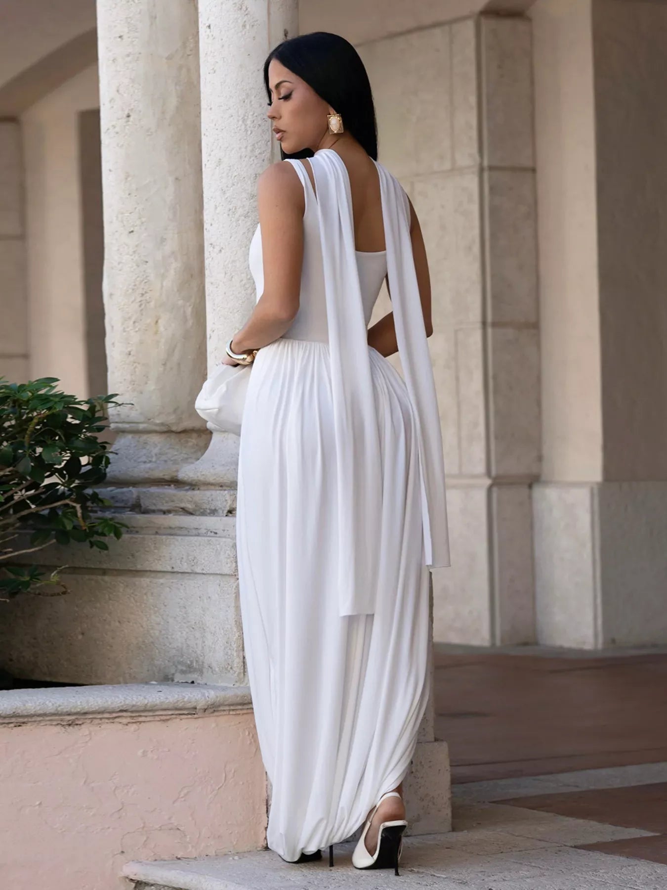 Woman in a white dress standing in front of classical architecture