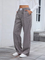 Person wearing black and white checkered pants with a white top outdoors.