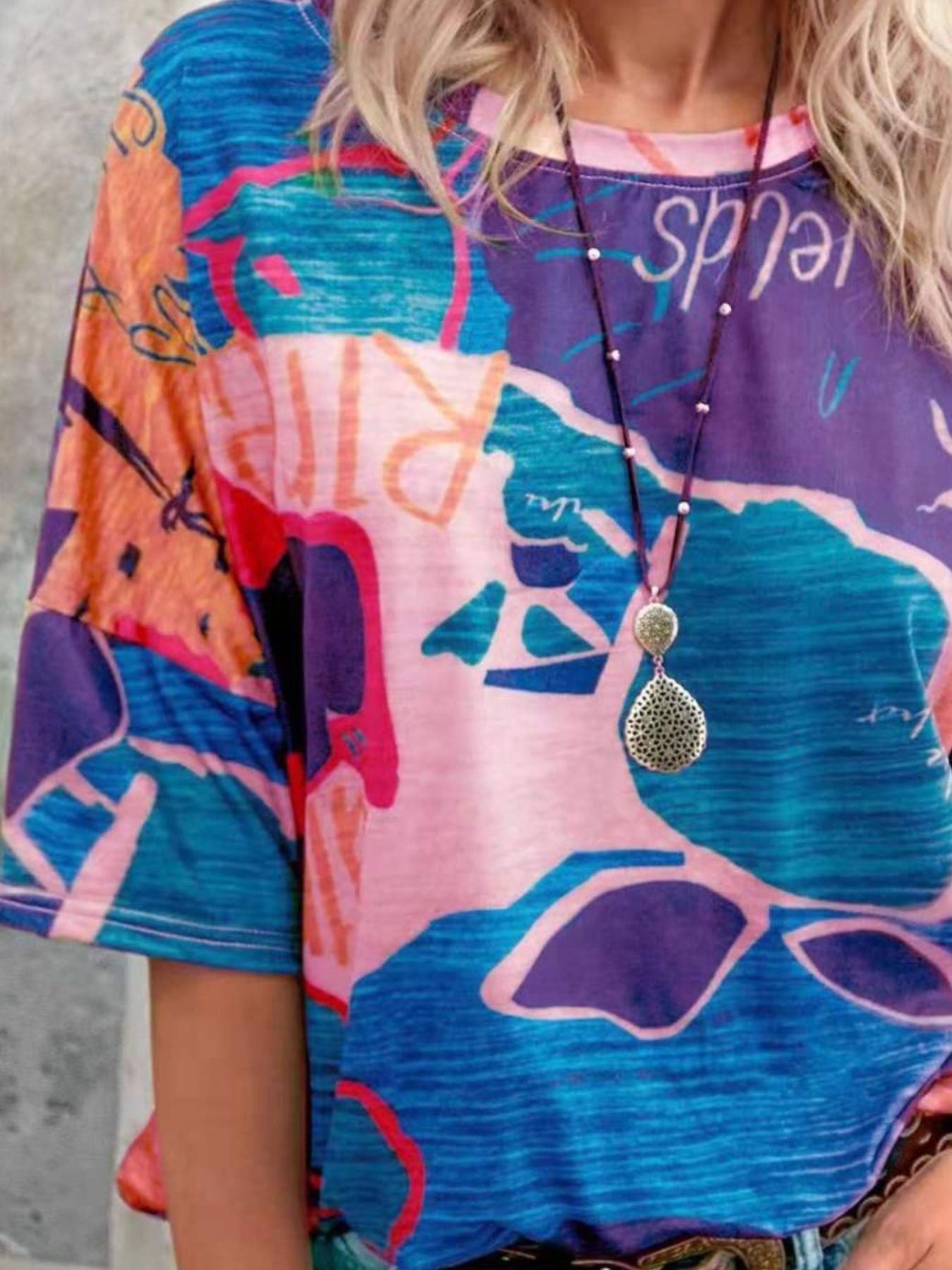 Colorful dress with abstract patterns and text, worn by a person.