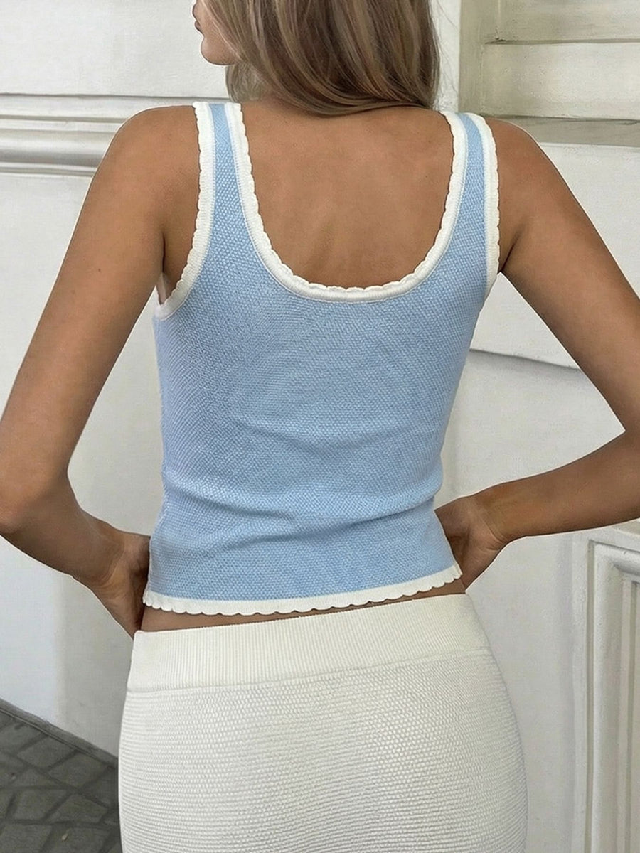 Woman wearing a light blue knit tank top with white trim against a neutral background