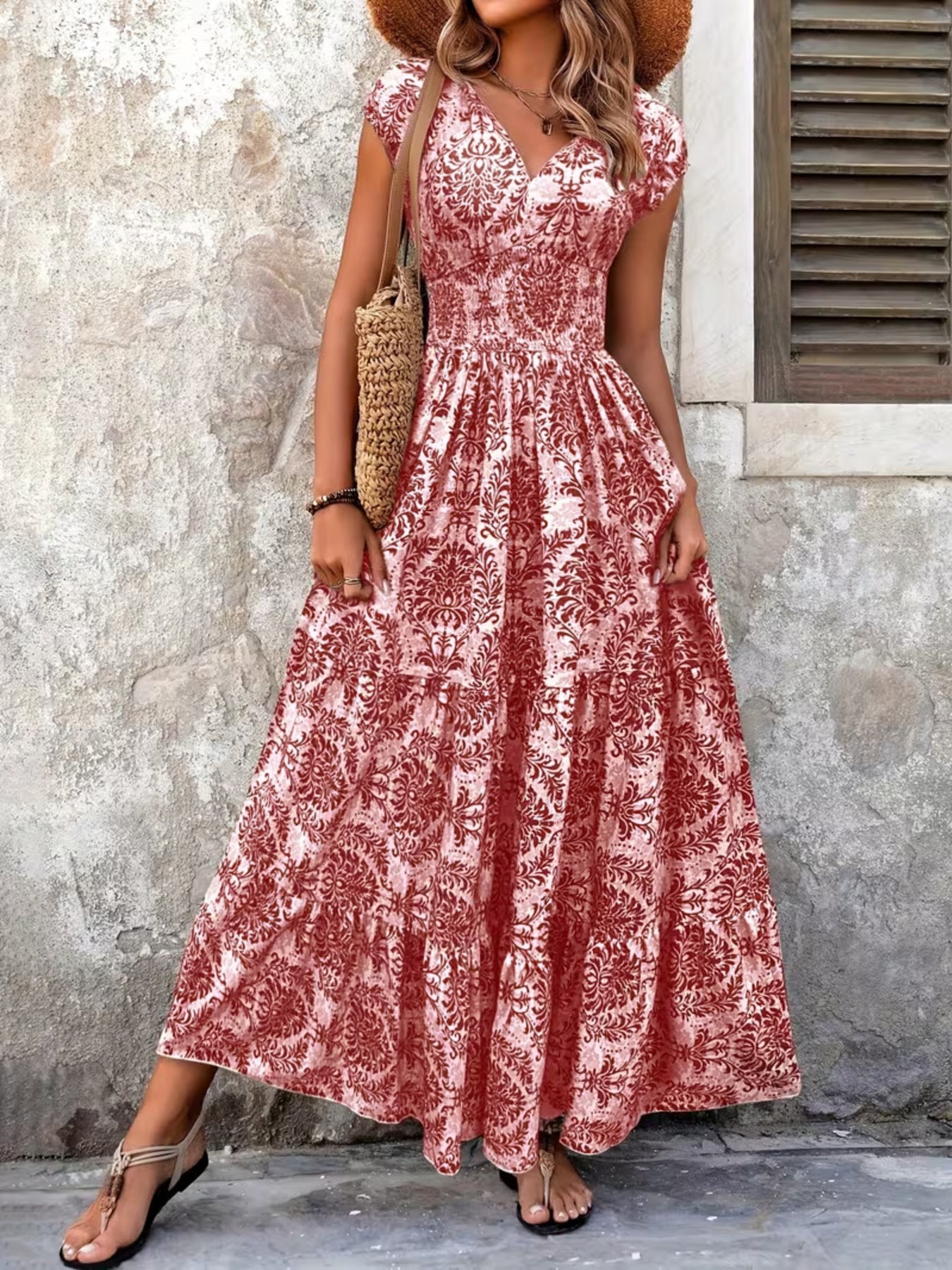 Woman wearing a red floral dress standing against a textured wall.