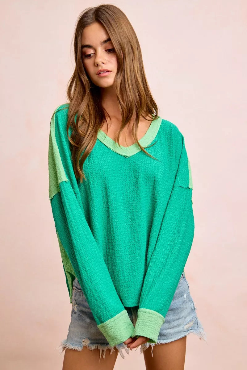 Woman wearing a green sweater with a pink background