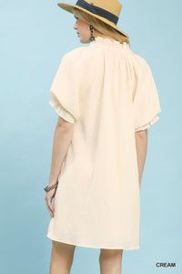 Woman wearing a cream dress and straw hat against a light blue background
