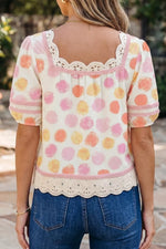 Woman wearing a polka dot blouse with lace details and blue jeans outdoors.