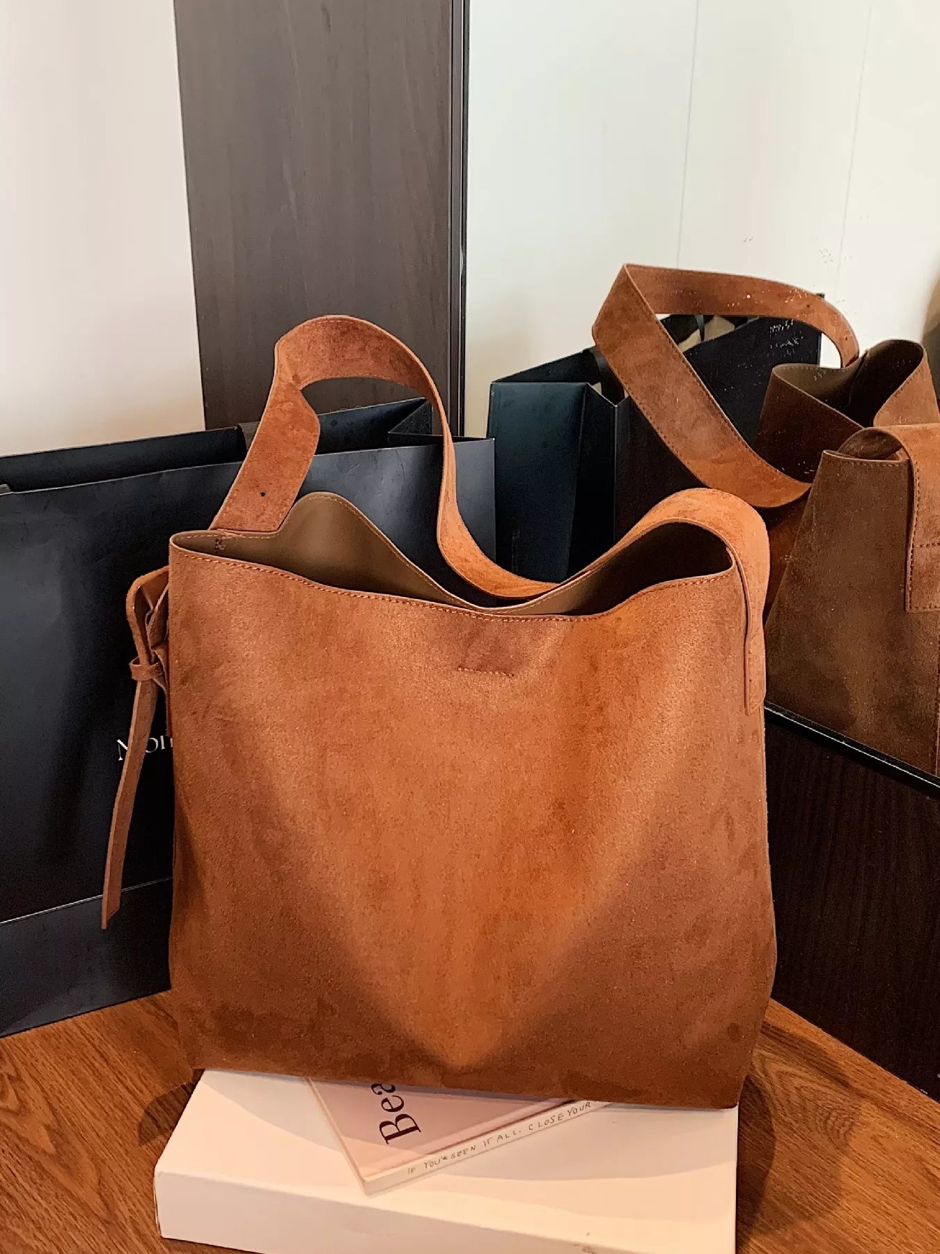 Brown leather handbag on a wooden surface with a blurred background