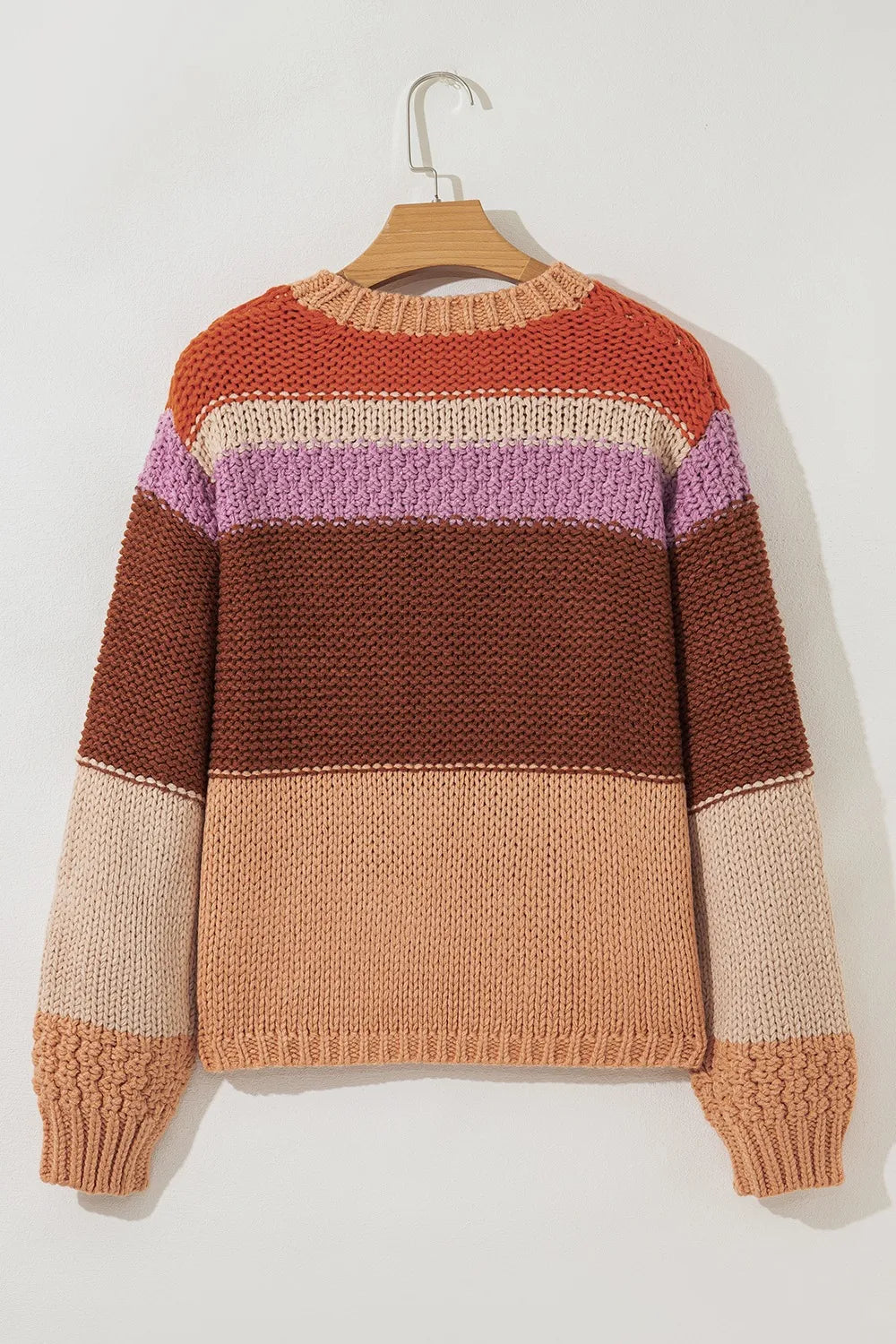 Color-blocked sweater on a hanger against a white background