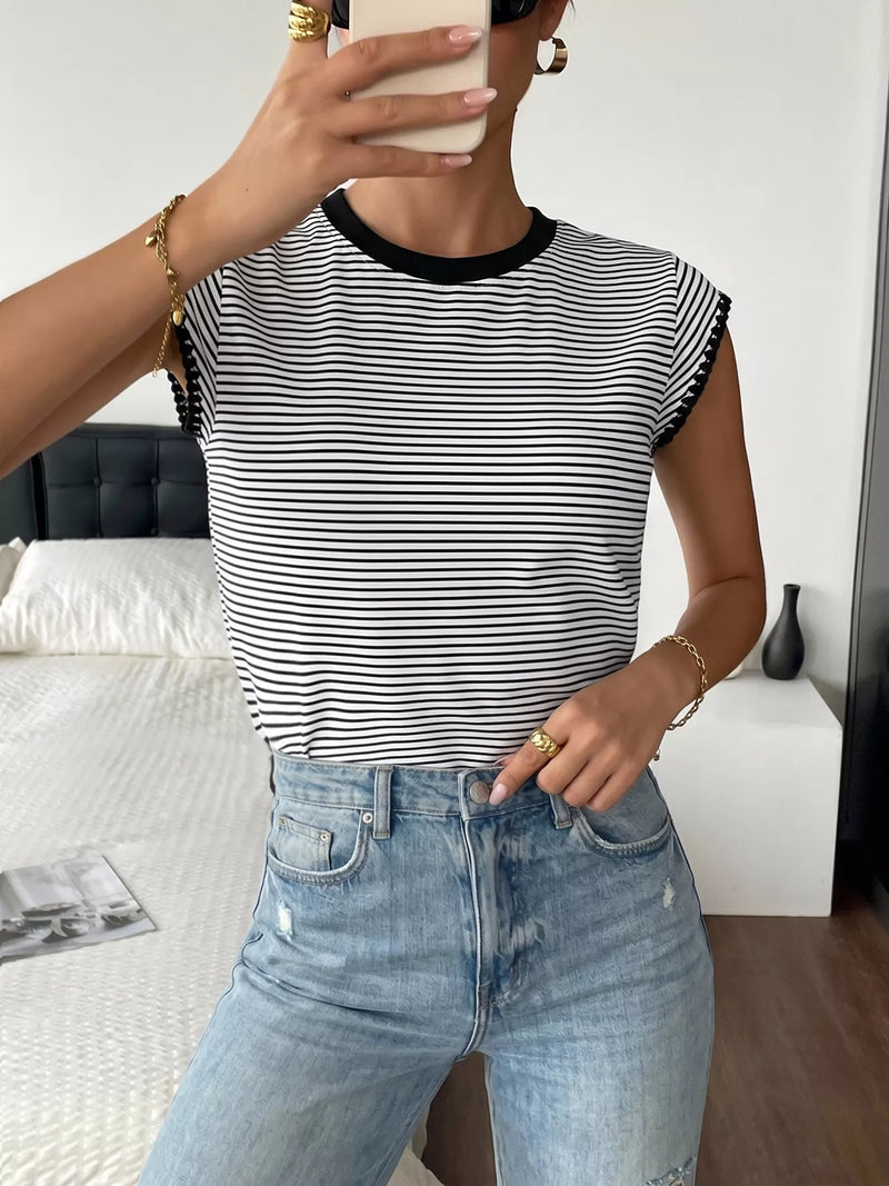 Person wearing a black and white striped shirt and blue jeans, holding a phone.
