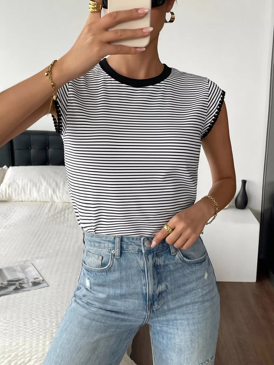 Person wearing a black and white striped shirt and blue jeans, holding a phone.