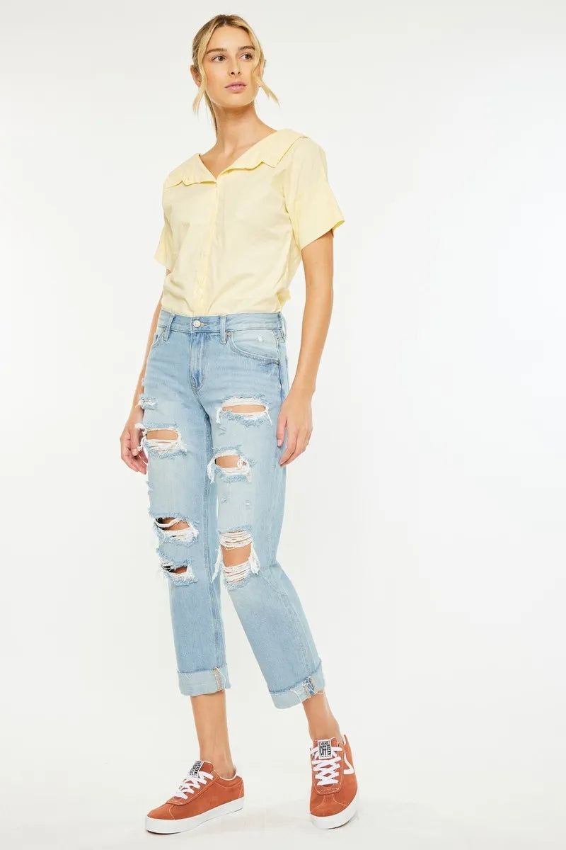 Woman wearing a yellow shirt and light blue ripped jeans on a white background
