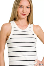 Woman wearing a white tank top with black stripes on a plain background