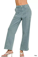Teal denim pants worn by a person on a white background
