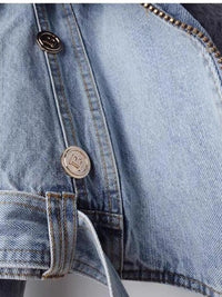 Close-up of a blue denim jacket with buttons and zippers.