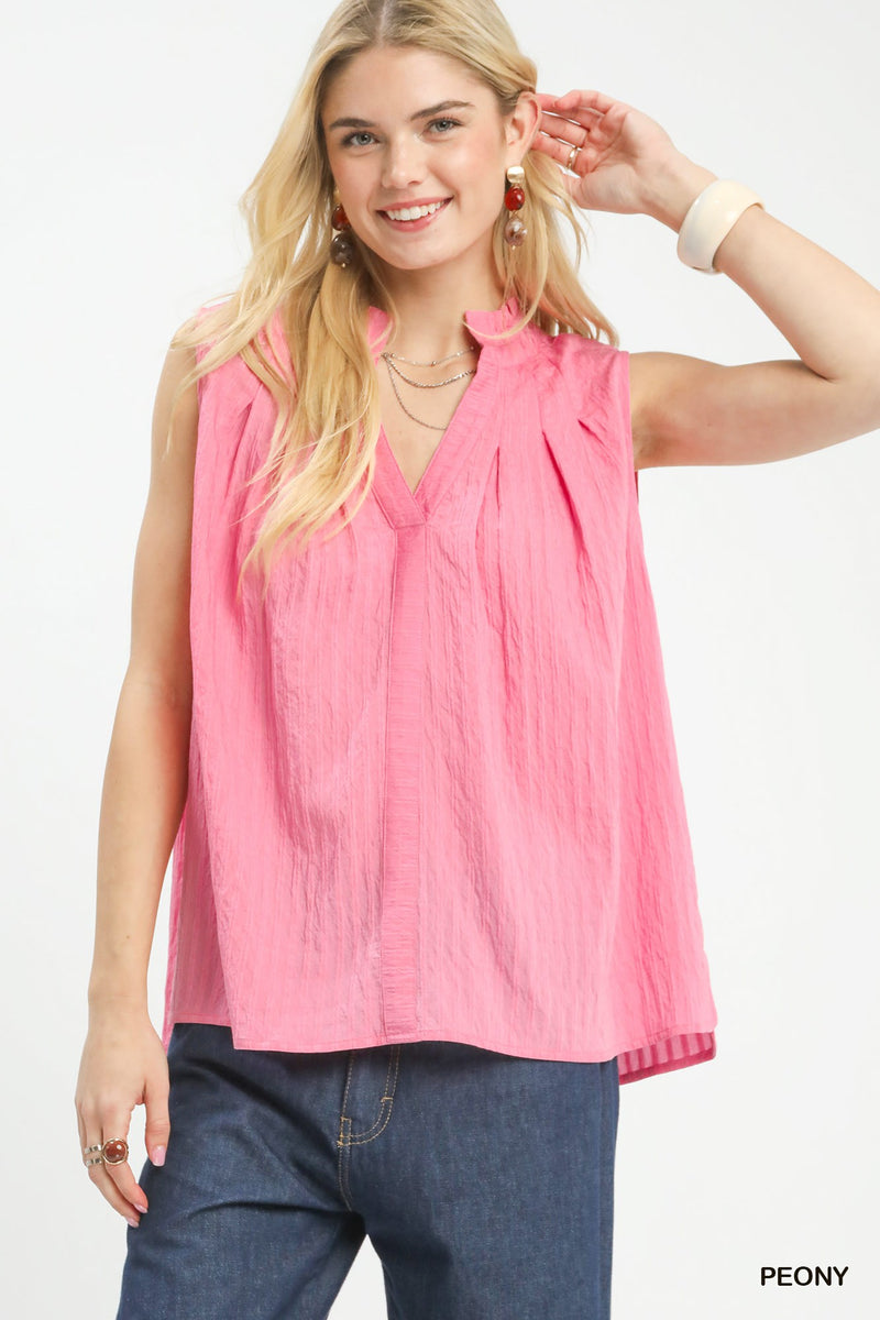 Woman wearing a pink sleeveless blouse with a plain background