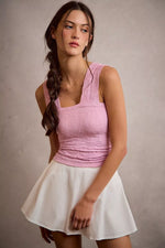 Woman wearing a pink top and white skirt against a plain background
