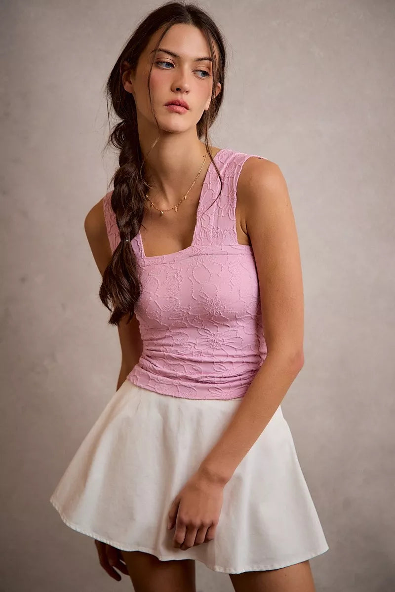 Woman wearing a pink top and white skirt against a plain background