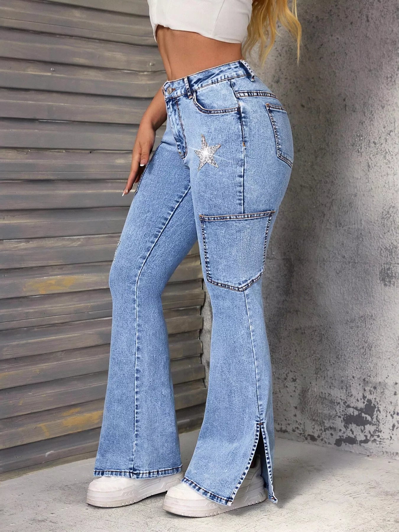 Person wearing high-waisted blue jeans with a decorative star patch against a textured wall.