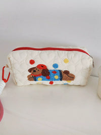 Quilted pouch with a embroidered dog design on a white surface