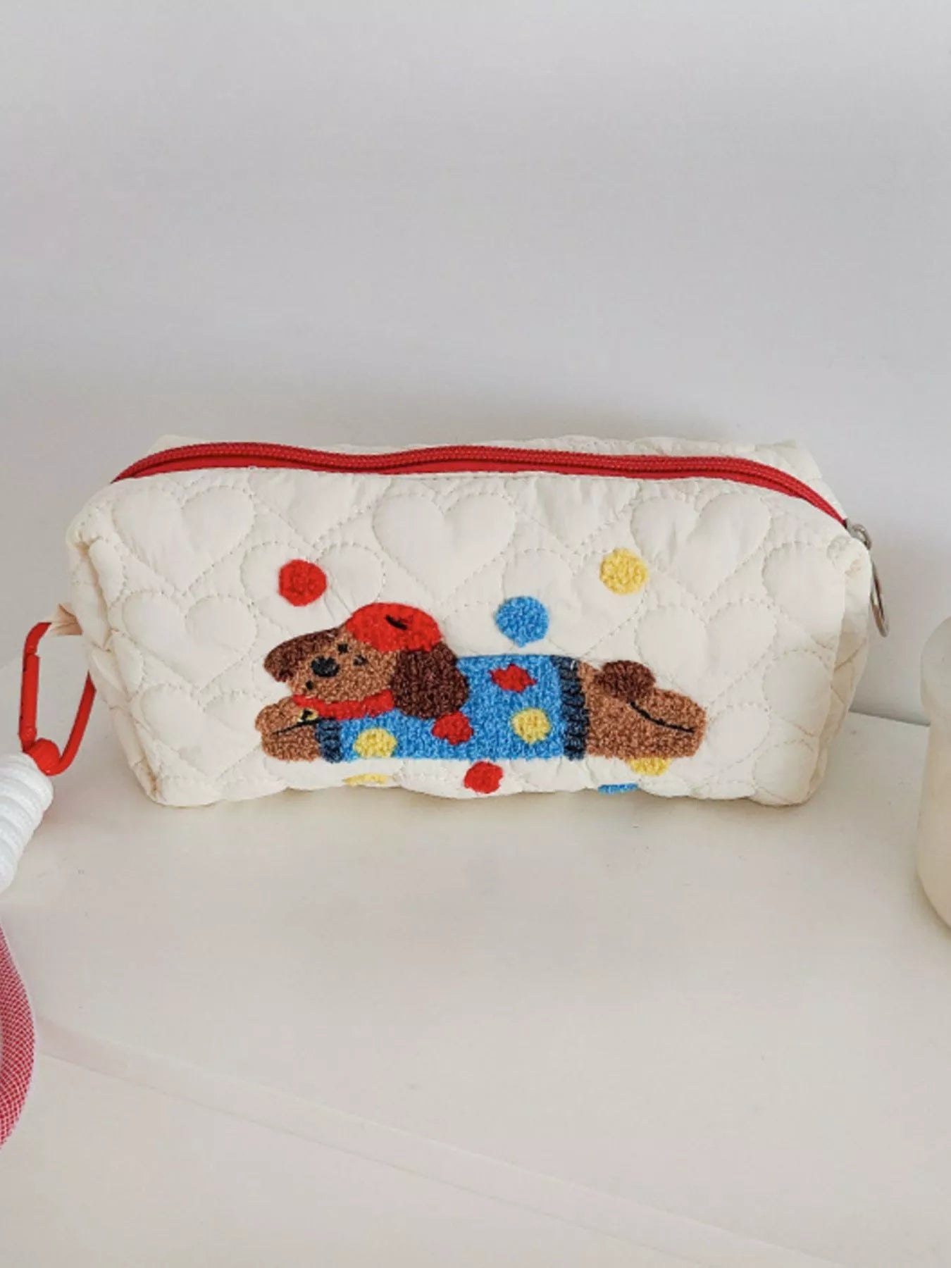 Quilted pouch with a embroidered dog design on a white surface