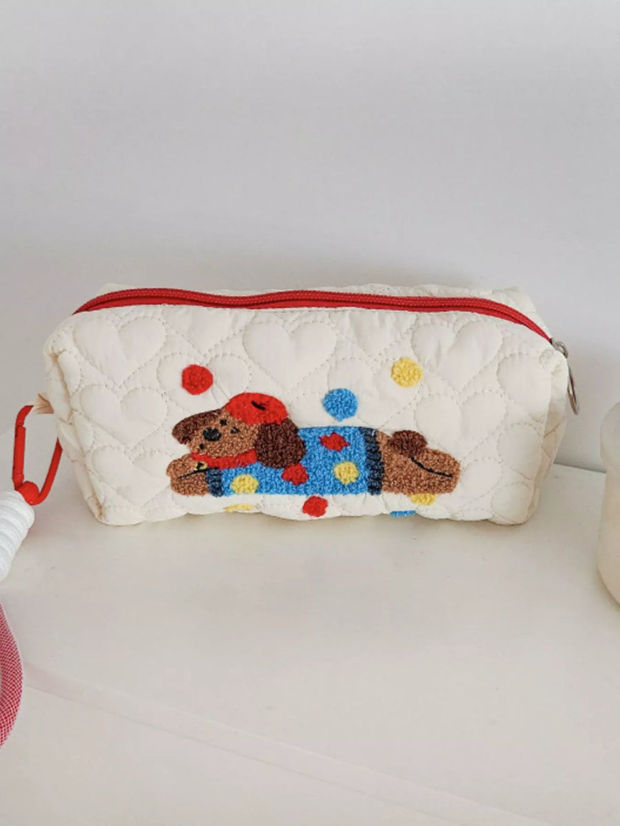 Quilted pouch with a embroidered dog design on a white surface