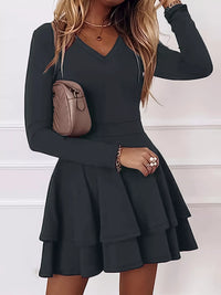 Black long-sleeve dress worn by a person with a neutral background