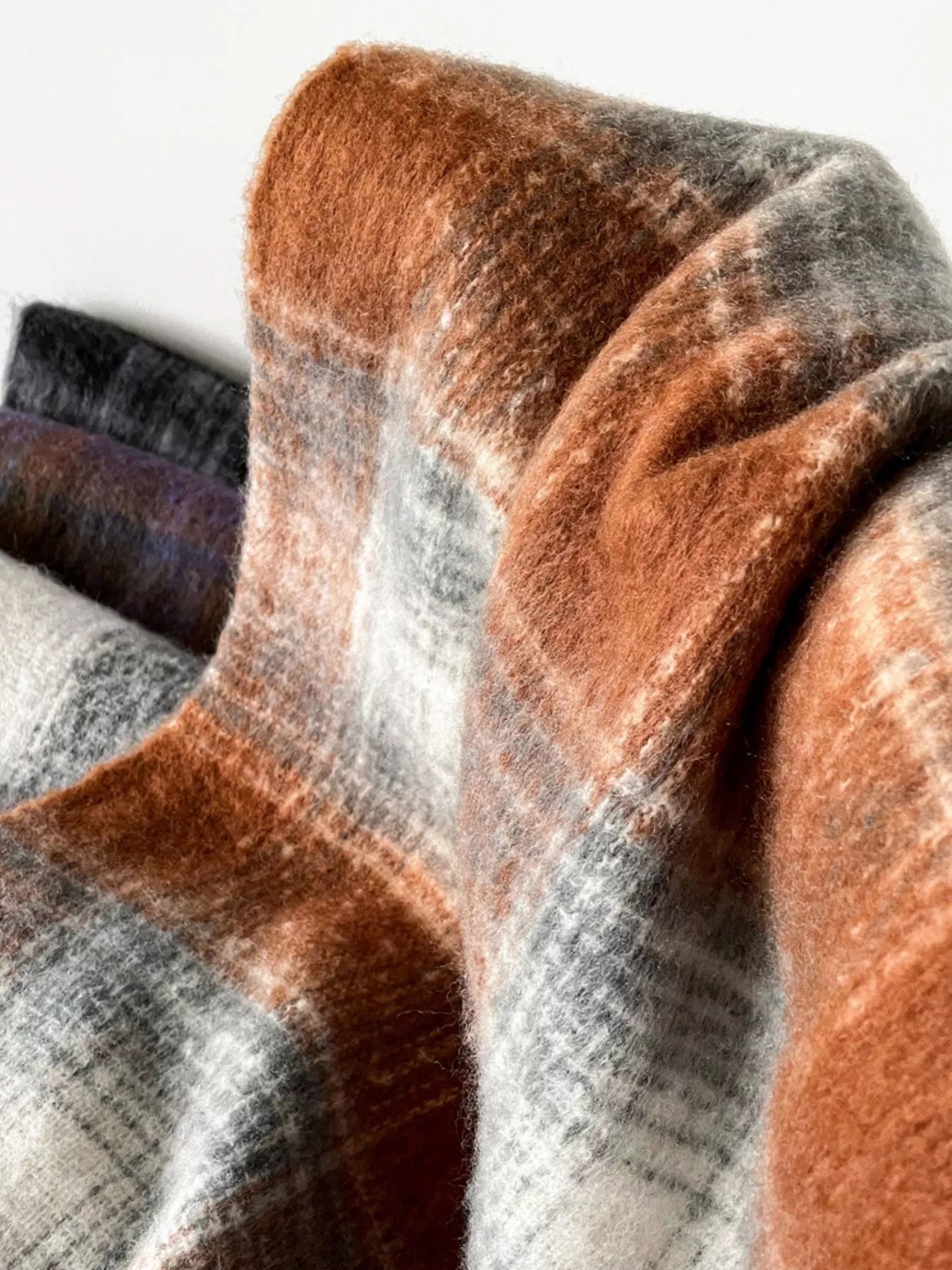 Close-up of plaid fabric in brown, gray, and purple colors.