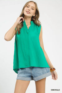 Woman wearing a green sleeveless top and denim shorts on a white background