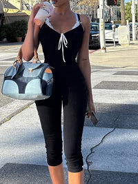 Person in black outfit holding a blue handbag on a city street